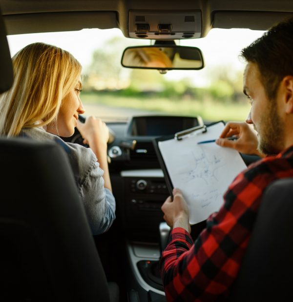 Instructor helps woman to drive the car