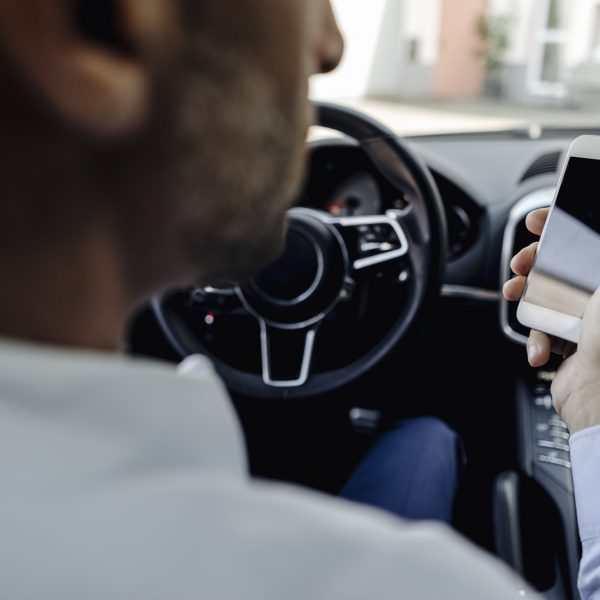 Businessman driving car looking at cell phone